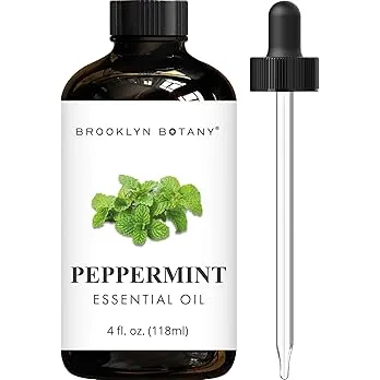 Bottle of peppermint essential oil with fresh peppermint leaves in the background.