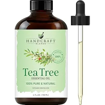 Bottle of tea tree essential oil with tea tree leaves in the background.